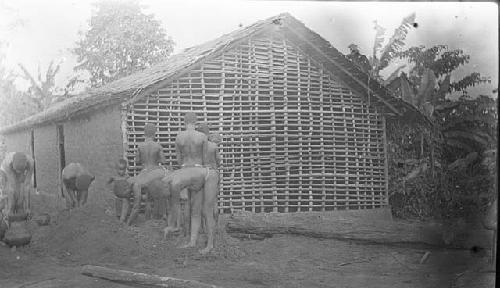 Hut construction process, People putting mud on hut