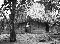 Man in doorway of dwelling house in jungle