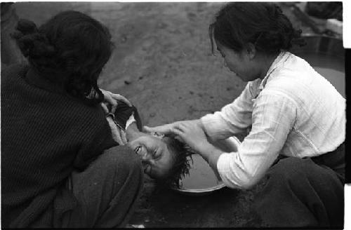 Two women washing a young boy