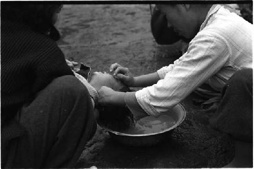 Two women washing a young child