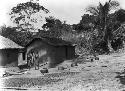 Man and boy in front of Basa hut