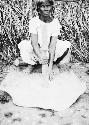 Woman beating clay to make pottery