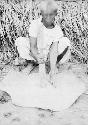 Woman beating clay to make pottery