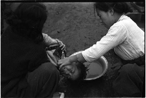 Two women washing a young child