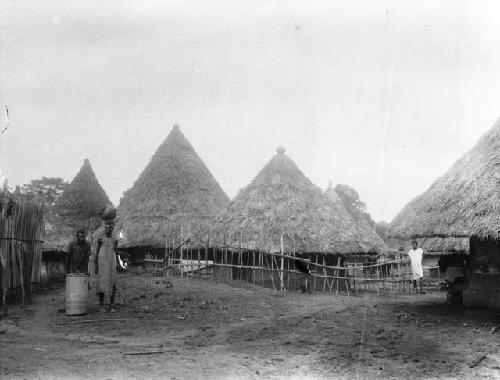 Man with basket and woman carrying bowl  in front of Yela town entrance