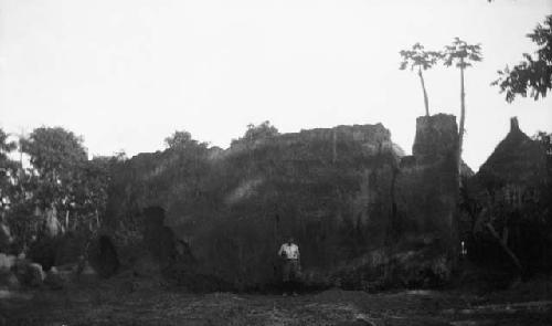 Man standing in front of large hut structure