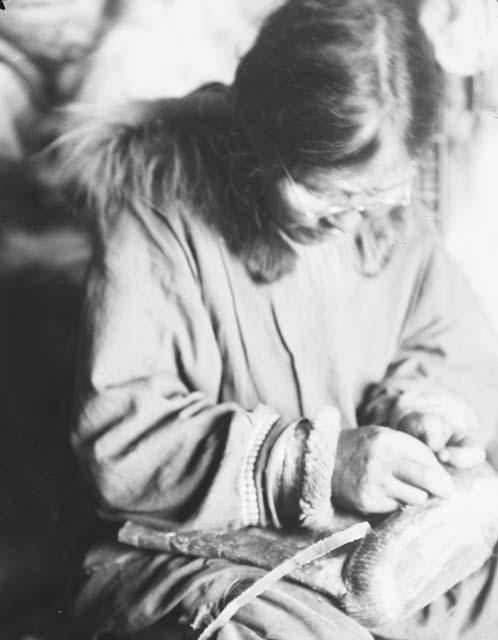 Native woman stitching boot soles of seal skin