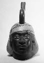 Red and white stirrup pot in form of human head, front view