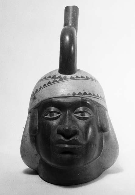 Red and white stirrup pot in form of human head, front view