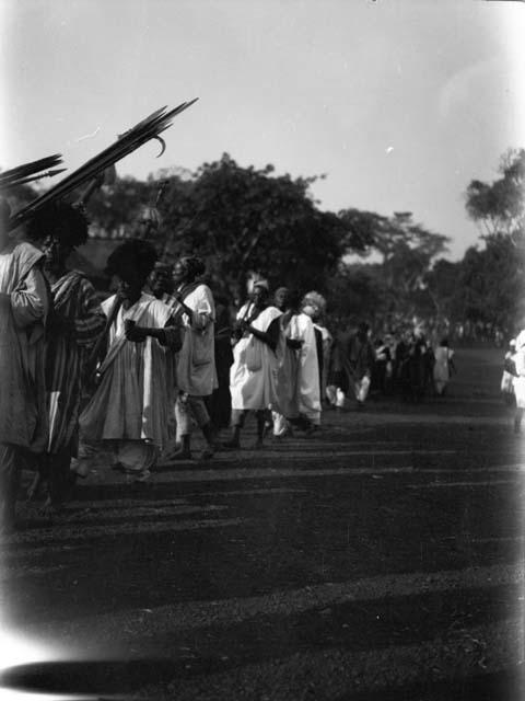 Men marching single file in Christmas parade for king