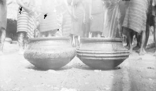 Two pots on ground with extensive decoration or carving