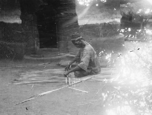 Man constructing mat out of plant material