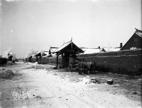 Man unloading donkey cart under small roofed structure