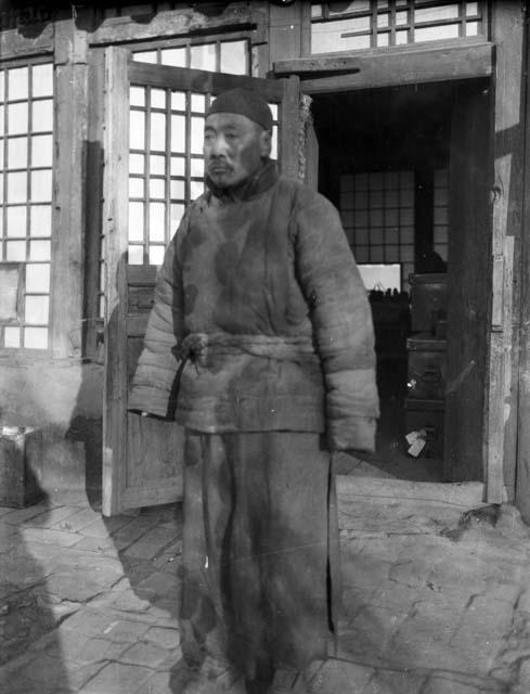 Portrait of an older man standing in front of a school building