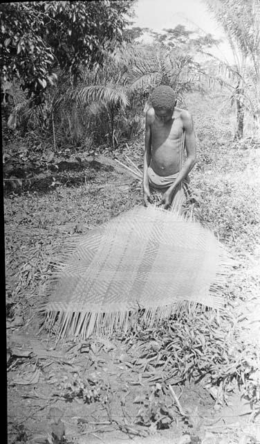 Man making a mat from stems