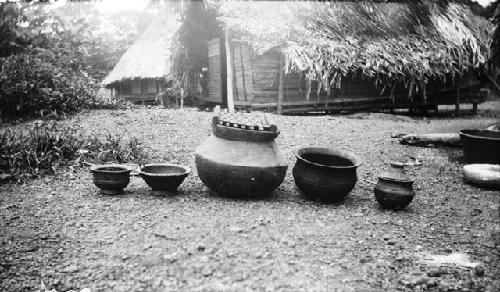 Group of pots in front of hut, Sapo, Pudu clan