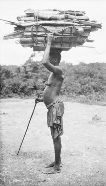 Woman carrying large bundle of wood on her head, Sapo, Pudu clan