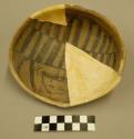 Fragments of black on yellow pottery bowl