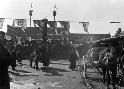 Carts horses and men in inn yard decorated with penants and other material