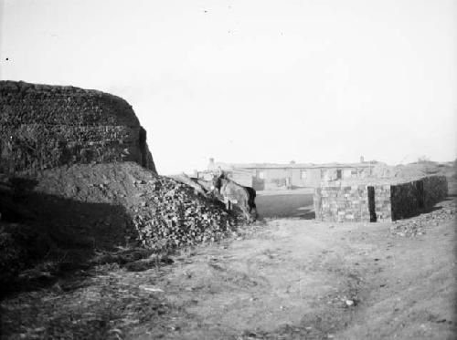 Close view of kiln, large pile of bricks, donkey, small buildings in background