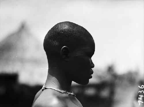 Profile view of young girl with necklace and facial scar tattooing