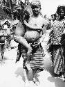 Woman with body scarification, carrying child with matted hair and cowry shells