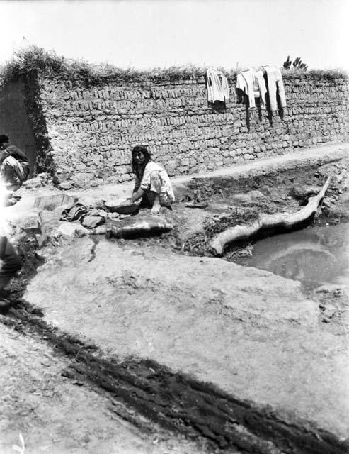 Turki girl washing clothes in basin by water