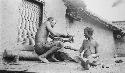 Man removing woman's bracelet with hammer and rock