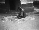 Man constructing mat out of plant material