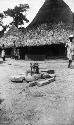 Man walking past village sacrificial place, stones around sticks