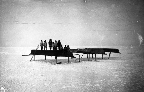 Oomiaks on their racks before whaling season, group of people