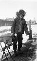 Peddler standing on street next to small display table