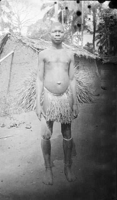 Young man in circumcisial dress in front of hut