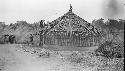 Men constructing circular hut with funnel shaped roof