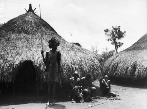 Group in front of hut, headman with spear and leopard skin clothing