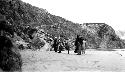 People standing on riverbank rocky hills in background