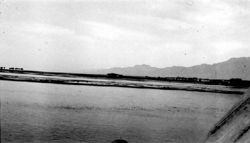 River, buildings on opposite shore, mountain background