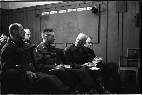 Military personnel sitting in a row of chairs