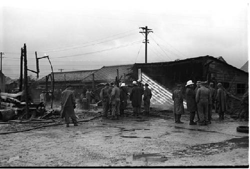 Firefighters and others outside a burned building