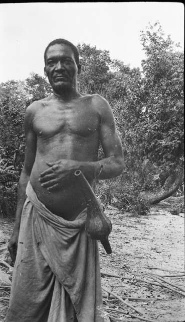 Man standing with gourd, containder or instrument