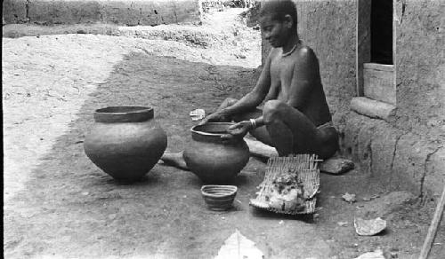 Woman making clay pots, one complete, two showing process