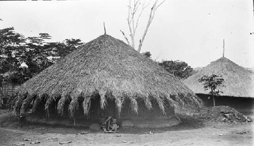 Men sitting outside completed Babutu circular hut