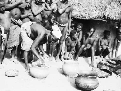 Group watching woman making clay pots