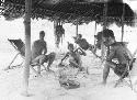 Group of men lounging around under canopy
