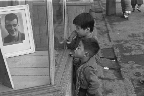 Two boys looking at G.I. photo in shop window