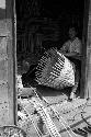 Two men in doorway of house making baskets.