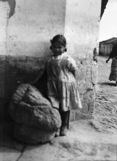 Little girl standing beside stone carving