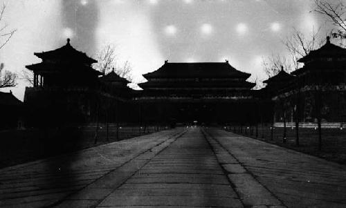 Wide walkway lined with trees leading to building complex