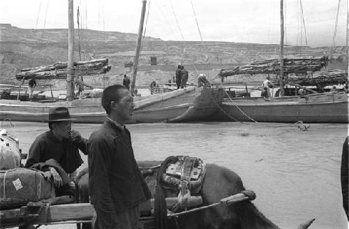 Two men and supplies on boat in foreground, more boats behind,