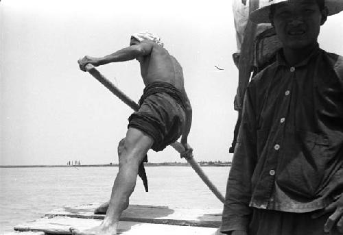 Man with pole in raft with back turned